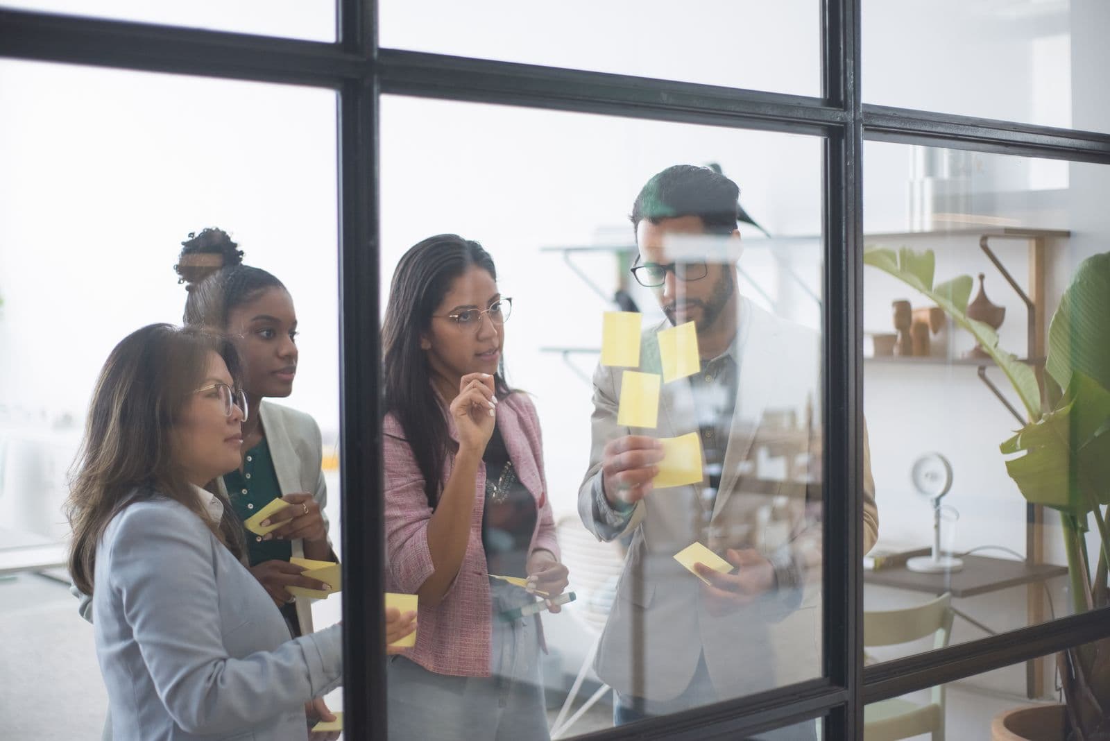 Creative team brainstorming with sticky notes on a glass wall